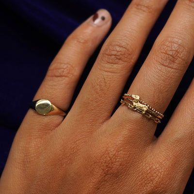 Close up view of a model's hand wearing an Dog Ring stacked with other Automic Gold rings