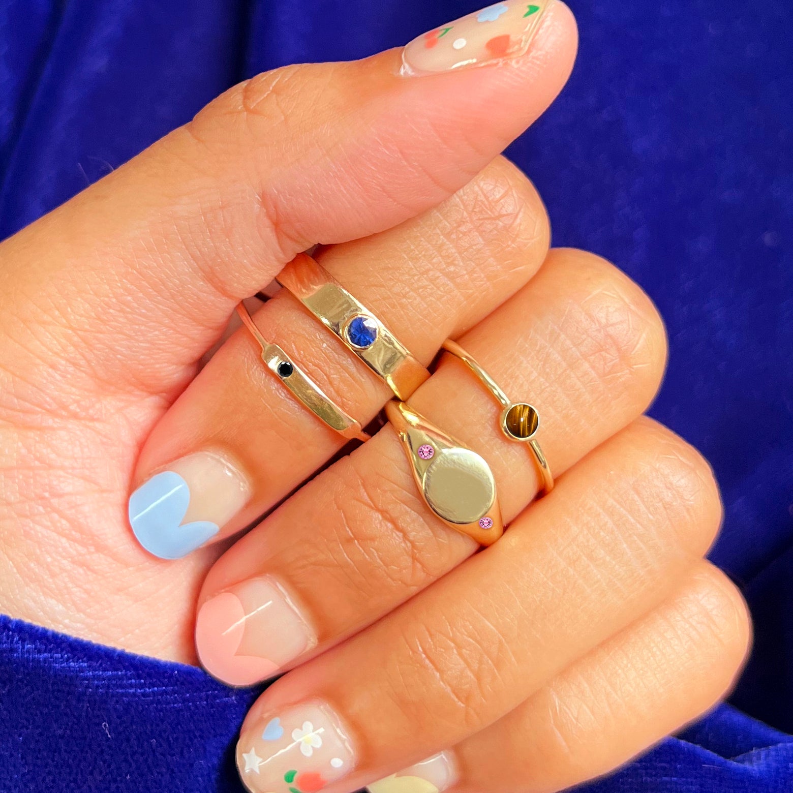 Close up view of a model's hand wearing a Pink Tourmaline Signet Ring and other Automic Gold Rings